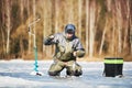 Winter fishing on ice. fisherman or angler hooking the fish Royalty Free Stock Photo