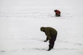 Winter fishing from the ice on the lake reservoir on a cold day. warmly dressed fishermen