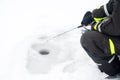 Winter fishing on ice. Man jiggling bait in an ice hole. Relaxing in the wild Royalty Free Stock Photo