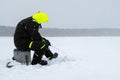 Winter fishing on ice. Man jiggling bait in an ice hole. Relaxing in the wild during snowfall Royalty Free Stock Photo