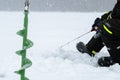 Winter fishing on ice. Man jiggling bait in an ice hole. Relaxing in the wild during snowfall Royalty Free Stock Photo