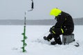 Winter fishing on ice. Man jiggling bait in an ice hole. Relaxing in the wild during snowfall Royalty Free Stock Photo