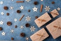 Winter flat lay with cinnamon, anise, cones, wooden snowflakes and gifts in craft paper on a blue textural background. Concept for Royalty Free Stock Photo