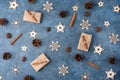 Winter flat lay with cinnamon, anise, cones, wooden snowflakes and gifts in craft paper on a blue textural background. Concept for Royalty Free Stock Photo