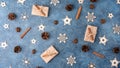 Winter flat lay with cinnamon, anise, cones, wooden snowflakes and gifts in craft paper on a blue textural background. Royalty Free Stock Photo