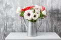 Winter flowers. Anemones in a vase watering can standing on a wooden table. On the background old gray wall art. copy Royalty Free Stock Photo