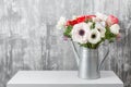 Winter flowers. Anemones in a vase watering can standing on a wooden table. On the background old gray wall art. copy Royalty Free Stock Photo