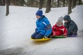 In winter, in the forest, children slide down the hill on plastic plates Royalty Free Stock Photo