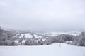 The winter forest is covered with fresh snow. The mountains and hills are completely white. Snow is falling, the sky is gray, Royalty Free Stock Photo