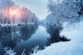 Winter forest on the river at sunset. Colorful landscape with snowy trees