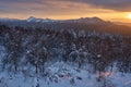 Winter forest with snow-covered fir trees high in the mountains. Dawn with bright colors on the horizon far away in the mountains Royalty Free Stock Photo