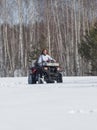 A winter forest. A woman with ginger hair in jacket riding snowmobile