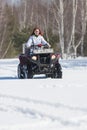 A winter forest. A woman with ginger hair riding snowmobile and overcoming the snow