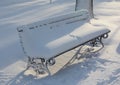 Winter frosty day in a park. An empty wrought iron bench in a park covered with snow during a frosty sunny day Royalty Free Stock Photo