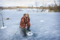 In winter, a girl in overalls caught a roach fish on the river