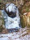 Winter Frozen Waterfall. Small Pond And Snowy Boulders Bellow Cascade