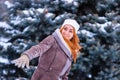 Winter ginger redhead girl throwing snowball at camera smiling happy having fun outdoors on snowing winter day playing in snow Royalty Free Stock Photo