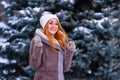 Winter ginger redhead girl throwing snowball at camera smiling happy having fun outdoors on snowing winter day playing in snow Royalty Free Stock Photo