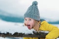 Winter girl eating snow outdoor. Funny christmas kids holiday. Kids cold and flu concept. Kid lick snow with tongue