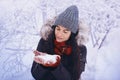 Winter girl in red gloves and scarf blowing snow. Beauty Joyful Teenage Model Girl having fun in winter park. Beautiful girl laugh Royalty Free Stock Photo