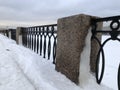 winter, granite pillar and cast iron embankment fence in the snow