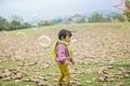 In winter, the ground is full of fallen leaves, and a child wearing a scarf plays on the green field Royalty Free Stock Photo