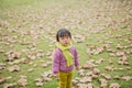 In winter, the ground is full of fallen leaves, and a child wearing a scarf plays on the green field Royalty Free Stock Photo