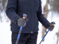 Winter hiking, details. Human hands with handles of nordic walking sticks, close up, selective focus.