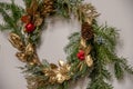 Ornate Christmas wreath of green conifer branches and metallic golden painted leaves with red berries and red Christmas bells Royalty Free Stock Photo