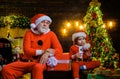 Winter holiday. Christmas decoration. Santa Claus with little helper near Christmas tree. Santa man and funny child boy Royalty Free Stock Photo