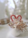 Winter holiday composition. Sweet candy heart, golden tinsel in white ceramic pot on bright background