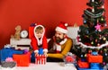 Winter holiday concept. Santa and little assistant among gift boxes Royalty Free Stock Photo