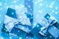 Winter holiday gifts and glowing snow on frozen blue background, Christmas presents surprise