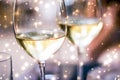 Winter holiday glasses of white wine and glowing snow on background, Christmas time romance