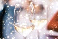 Winter holiday glasses of white wine and glowing snow on background, Christmas time romance Royalty Free Stock Photo