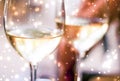 Winter holiday glasses of white wine and glowing snow on background, Christmas time romance Royalty Free Stock Photo