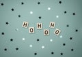 Winter Holiday Layout with Wooden Blocks with `Ho Ho Ho` and Glowing Confetti of Star Shape on a Light Blue Background. Royalty Free Stock Photo