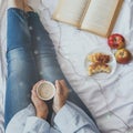 Winter holidays. Autumn morning. Woman having breakfast in bed. Coziness weekend morning. Woman with cup of coffee latte in hands Royalty Free Stock Photo