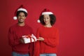 Winter holidays celebration. Young african american smiling man offering Christmas gift Royalty Free Stock Photo