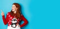 Winter holidays and Christmas Eve concept. Happy and cute redhead girl in xmas sweater, looking and pointing at upper