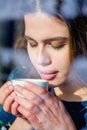 Winter holidays, christmas, hot drinks and people concept. Beautiful young woman tourist in warm clothes drinking coffee from Royalty Free Stock Photo