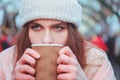 Winter holidays, christmas, hot drinks and people concept. Happy beautiful young woman in warm clothes drinking coffee from Royalty Free Stock Photo