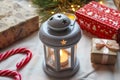 Winter holidays in cozy home. Lantern with candle, gifts, candy canes and pine branches. Christmas and New Year background. Royalty Free Stock Photo