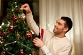 Happy man decorating christmas tree at home Royalty Free Stock Photo