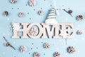 Winter holidays word home with snow painted pine cones and stars on blue background.