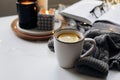 Winter home cozy concept.Cup of tea with lemon, open book, warm sweater, candles and fir tree. Wellbeing, relaxing concept