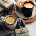 Winter home cozy concept. Hot tea with lemon, open book, warm sweater, candles and fir tree. Wellbeing, relaxing concept