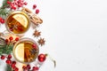 Winter hot tea with fruit, berries and spices on white table.