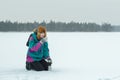 Winter hunkering hiker woman drinking hot tea from vacuum flask metal cup