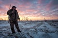 Winter hunting at sunrise. Hunter moving With Shotgun